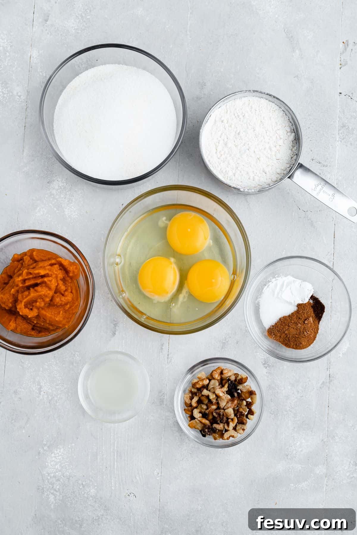 Clockwise from top: flour, spices, walnuts, lemon juice, pumpkin puree, sugar. Center: 3 eggs.