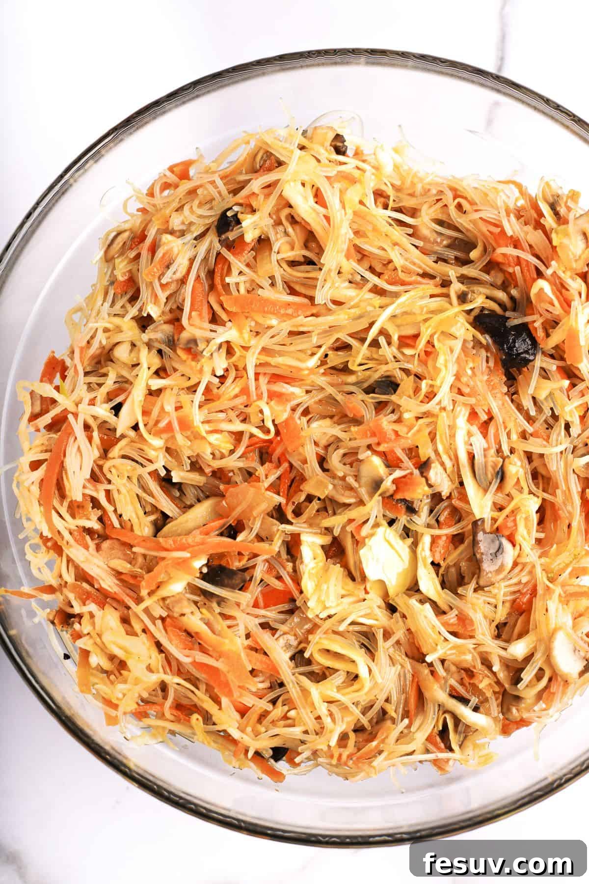 Sun-Kissed Vegetable Spring Rolls 4 A vibrant bowl of spring roll filling, featuring delicate rice vermicelli, shredded carrots, chopped mushrooms, and other savory vegetables.