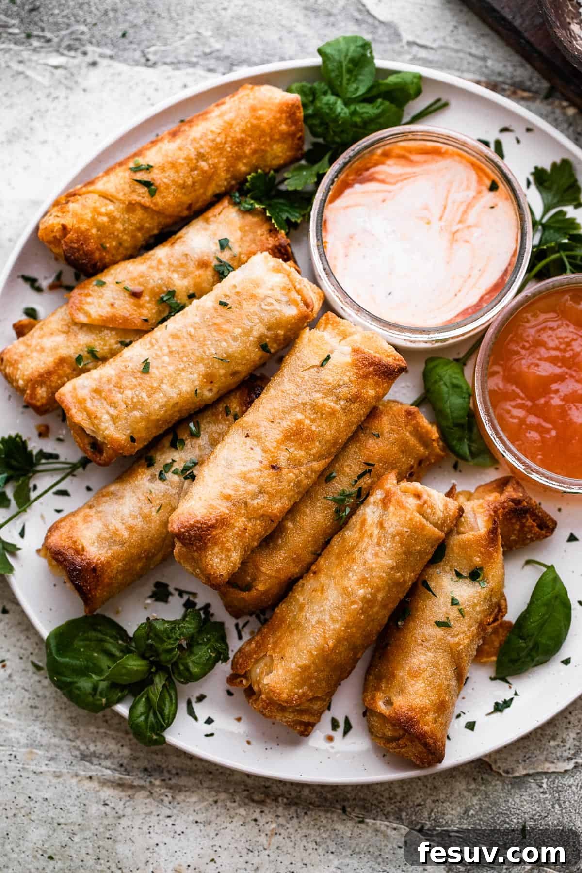 Sun-Kissed Vegetable Spring Rolls 6 A beautifully arranged plate of freshly fried spring rolls, served with a small bowl of vibrant dipping sauce.