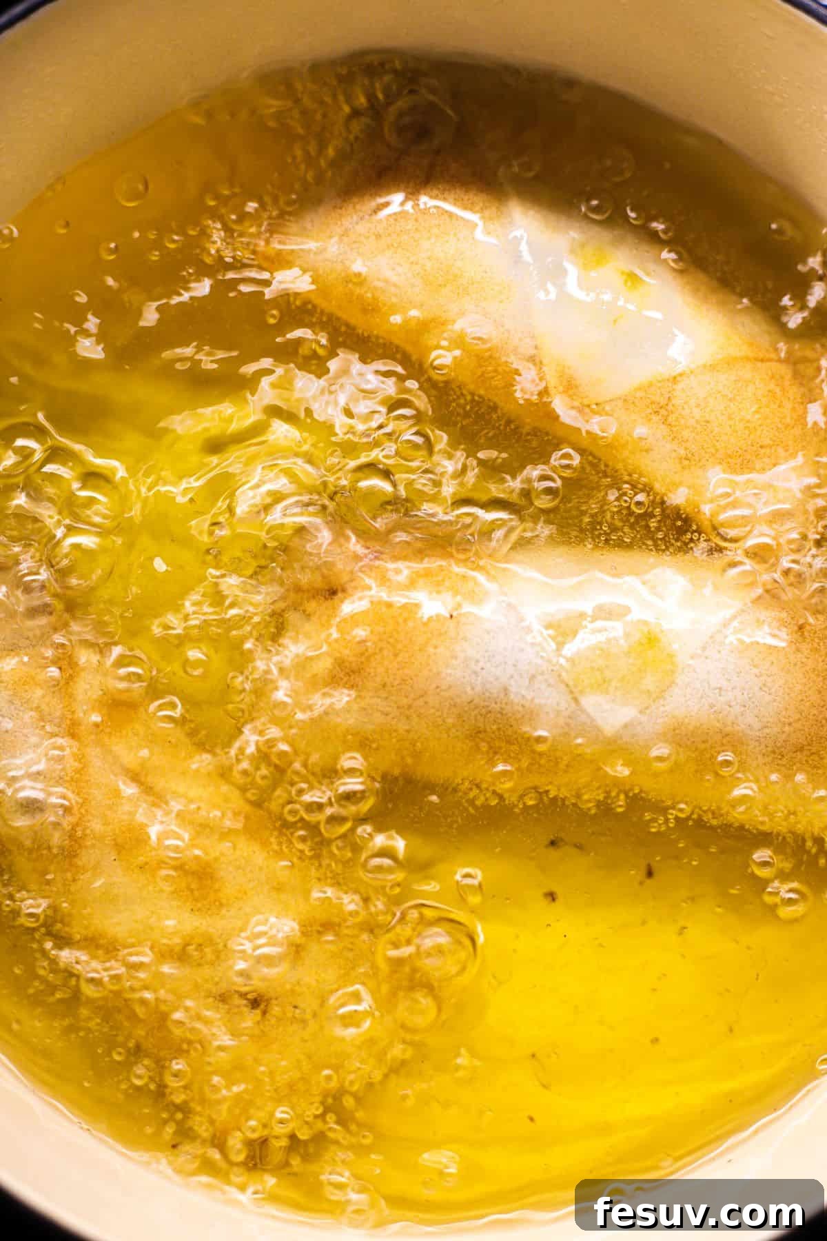 Sun-Kissed Vegetable Spring Rolls 7 Several spring rolls sizzling as they deep fry in hot oil within a skillet, turning golden brown.