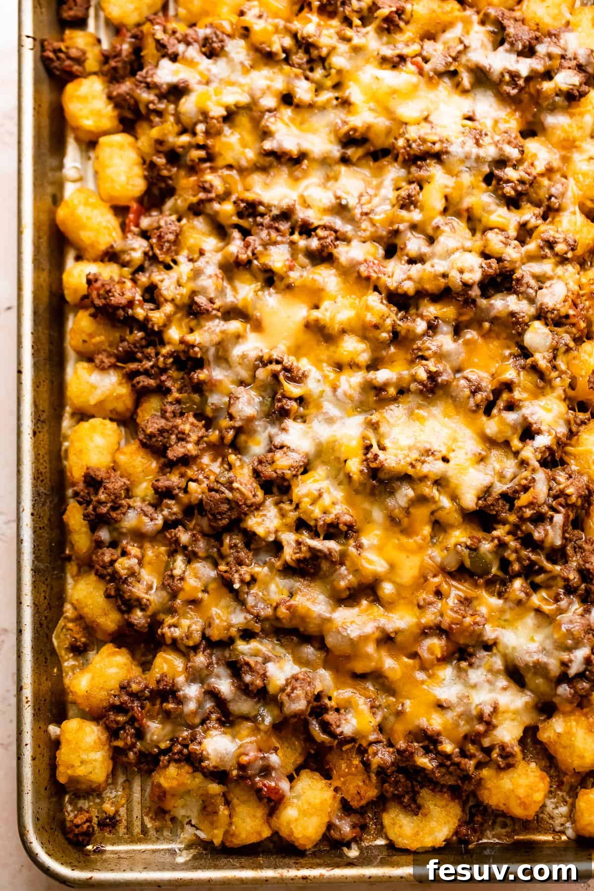 Loaded Sheet Pan Beef Totchos 5 A baking sheet of hot totchos, freshly pulled from the oven, with ground beef and melted cheese bubbling over crispy tater tots.