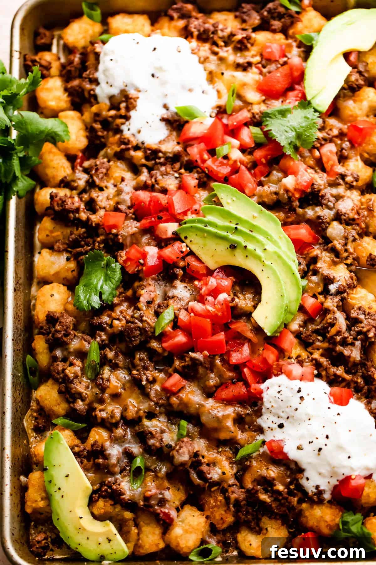 Loaded Sheet Pan Beef Totchos 7 A final shot of the completed sheet pan totchos, garnished beautifully with a colorful array of fresh toppings like tomatoes, sour cream, and avocado, showcasing their vibrant appeal.