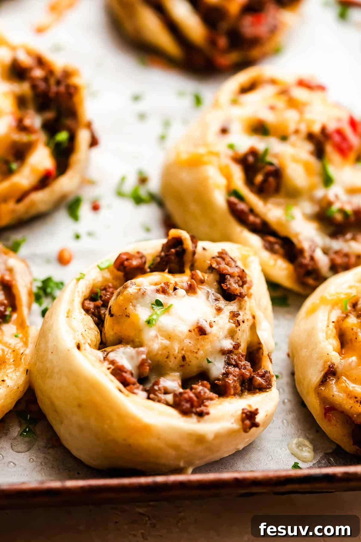 Freshly baked taco pinwheels with golden-brown crusts on a baking sheet, ready to be served.