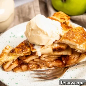 The Secret to Incredible Homemade Apple Pie 2 A freshly baked slice of apple pie, topped with a scoop of vanilla ice cream, on a plate with a fork.