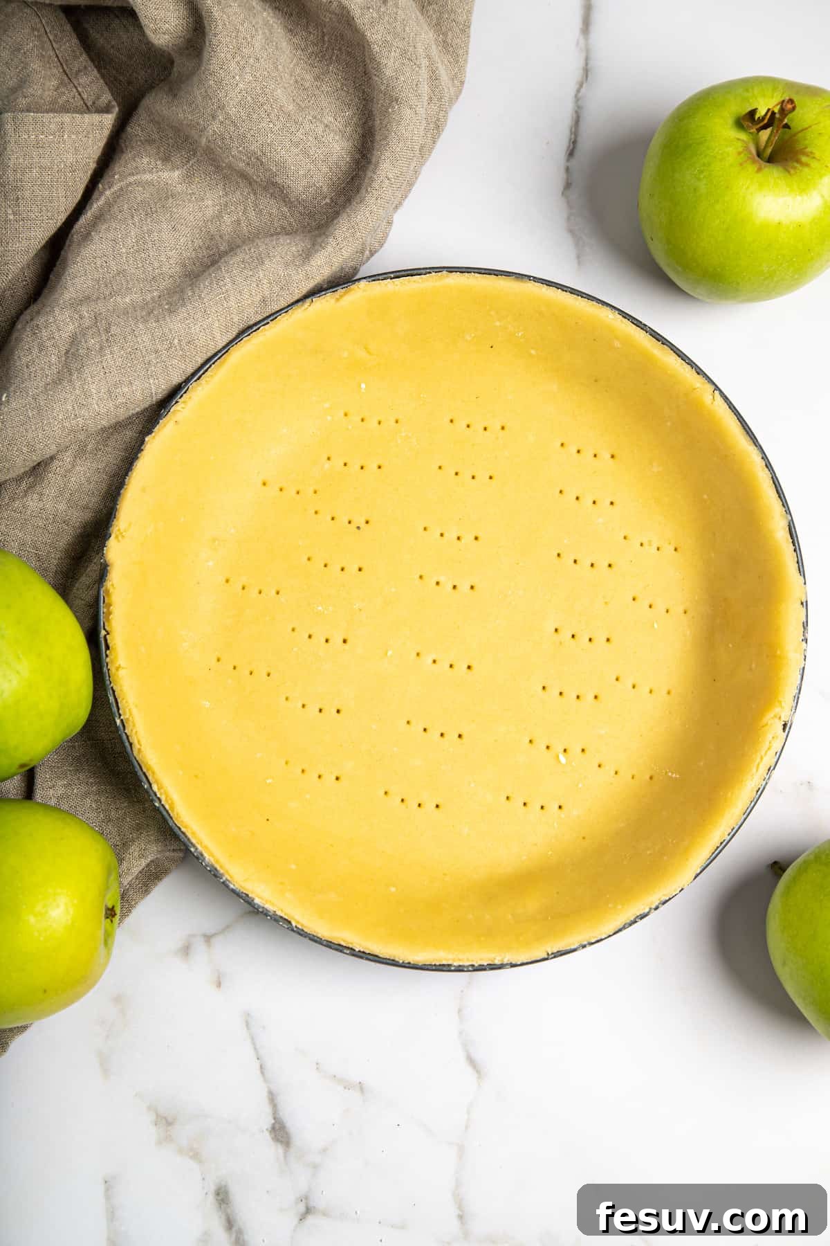 This classic yet easy and delicious Apple Pie recipe is made from scratch, with a buttery, flaky pie crust, fresh apple slices, pie spices, and brown sugar. A prepared pie shell, neatly placed in a pie plate, with crimped edges and ready for filling.