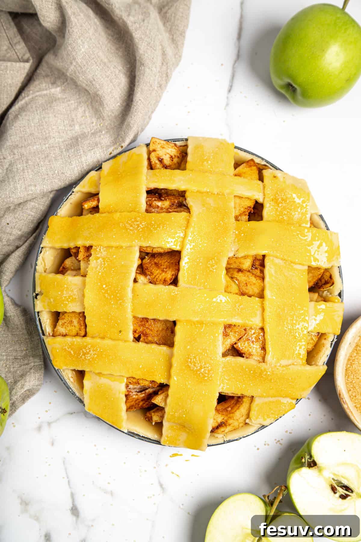 This classic yet easy and delicious Apple Pie recipe is made from scratch, with a buttery, flaky pie crust, fresh apple slices, pie spices, and brown sugar. An unbaked apple pie with a beautifully woven lattice top crust, brushed with egg wash and ready for the oven.