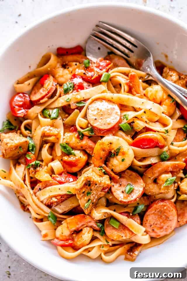 Close-up of One Pot Jambalaya Pasta in a white bowl, garnished with fresh herbs, ready to be enjoyed.