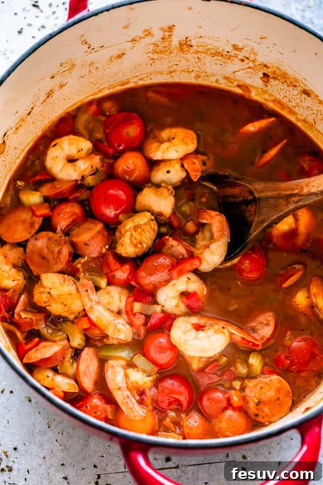 Chicken, sausage, and shrimp cooking together in a large pot, infused with rich Cajun spices.
