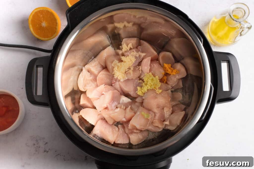Cubed chicken pieces placed inside an Instant Pot, ready for sautéing.