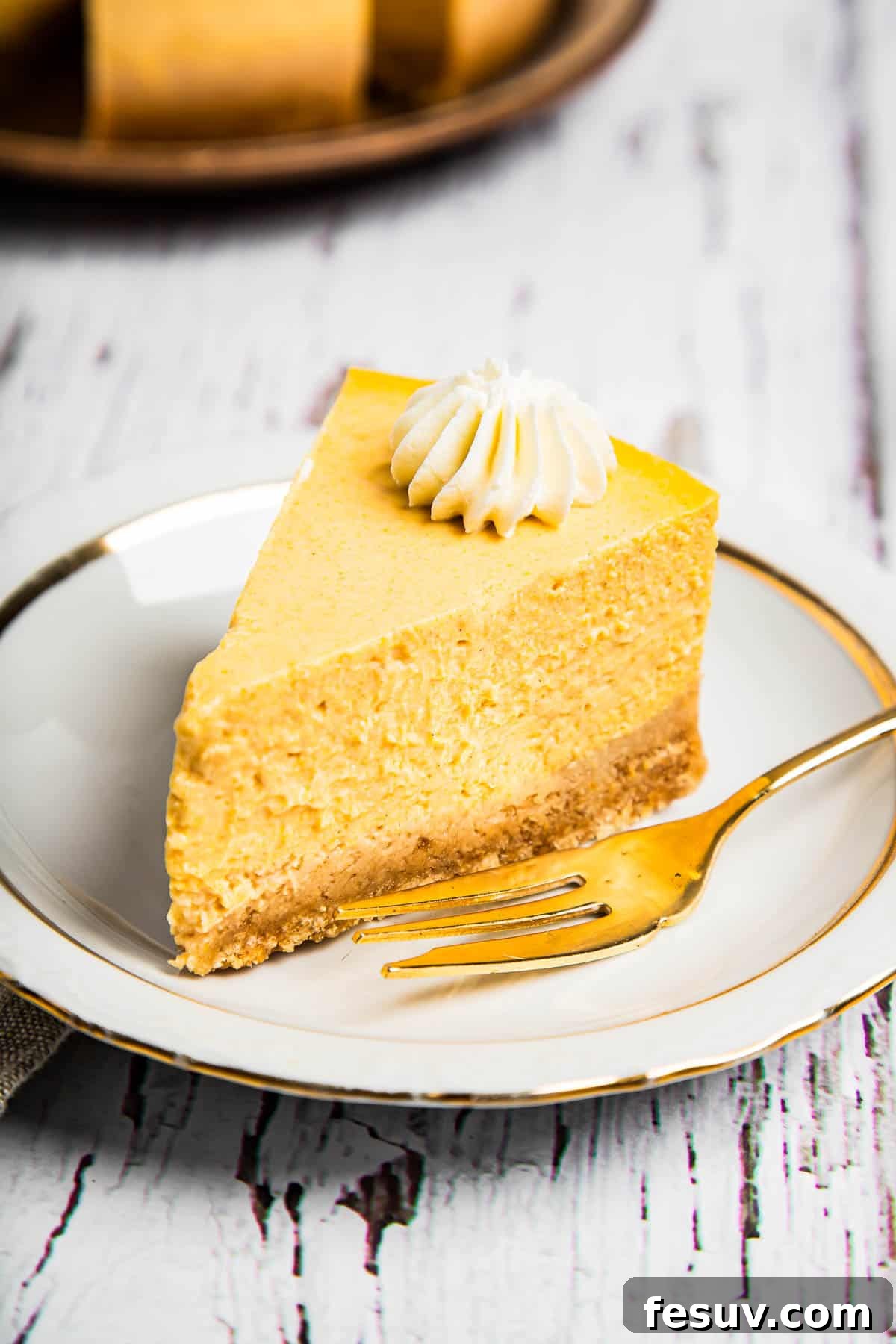 Creamy Instant Pot Pumpkin Cheesecake Bliss 2 A perfectly sliced Instant Pot Pumpkin Cheesecake with a golden fork on a saucer, ready to be enjoyed.
