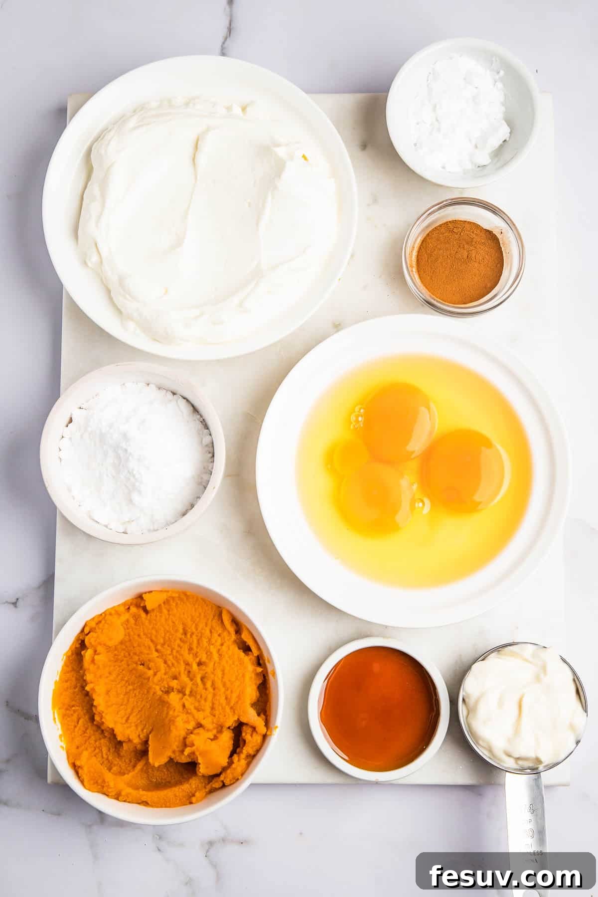 Creamy Instant Pot Pumpkin Cheesecake Bliss 3 Overhead shot of various bowls containing fresh ingredients for making Instant Pot Pumpkin Cheesecake, including pumpkin puree, cream cheese, and spices.