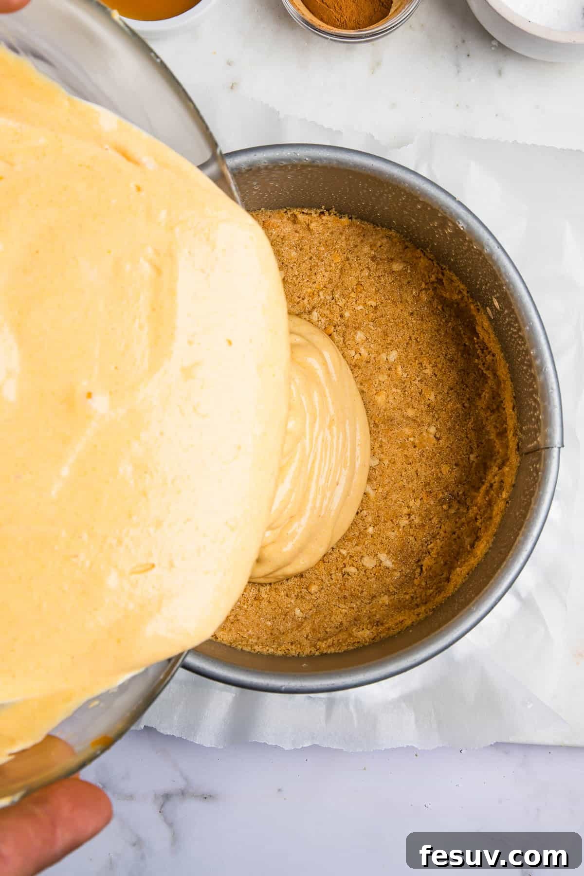 Creamy Instant Pot Pumpkin Cheesecake Bliss 4 Pouring smooth pumpkin cheesecake batter over a chilled graham cracker crust inside a springform pan, ready for the Instant Pot.