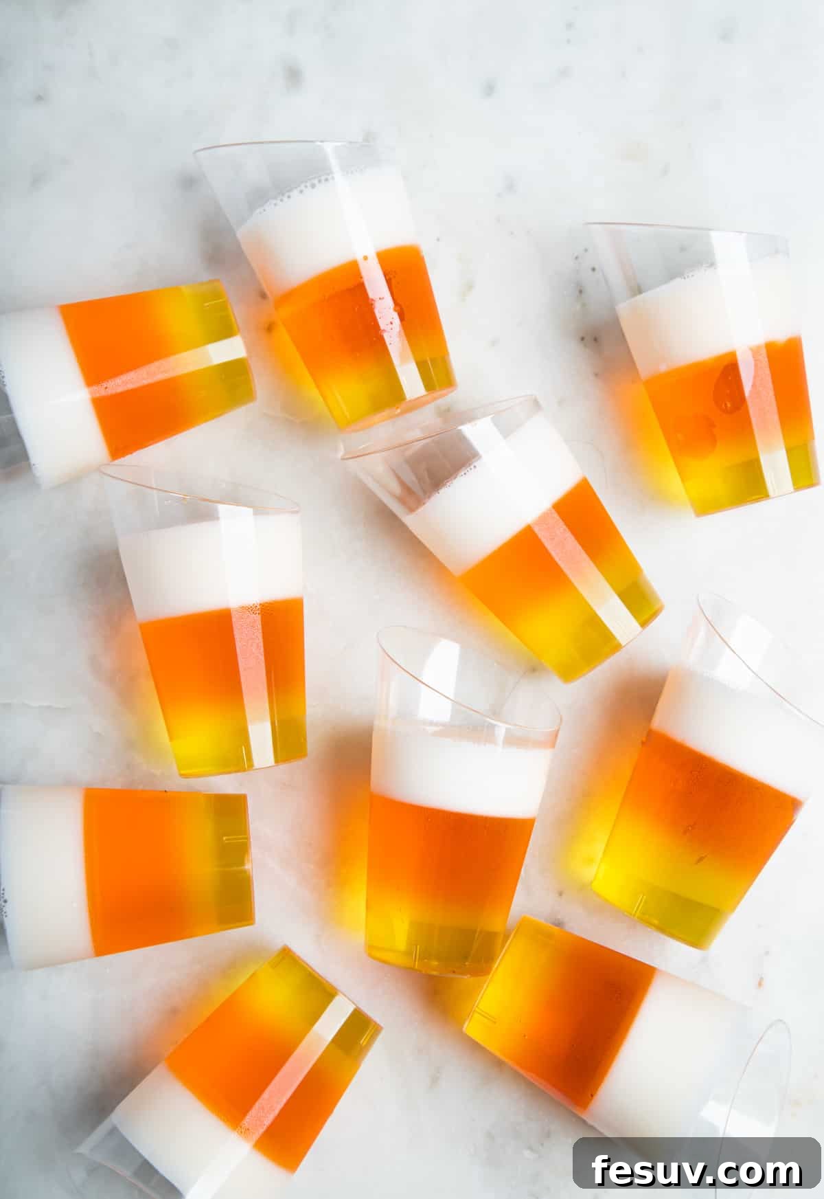 Vibrant Vodka Candy Corn Shooters 2 10 candy-corn jello shots scattered on a white table.