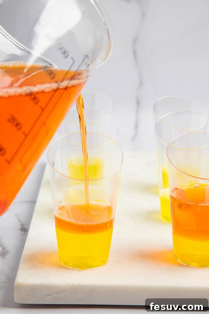 Vibrant Vodka Candy Corn Shooters 5 Orange jello added to shot glasses with lemon jello at the bottom.