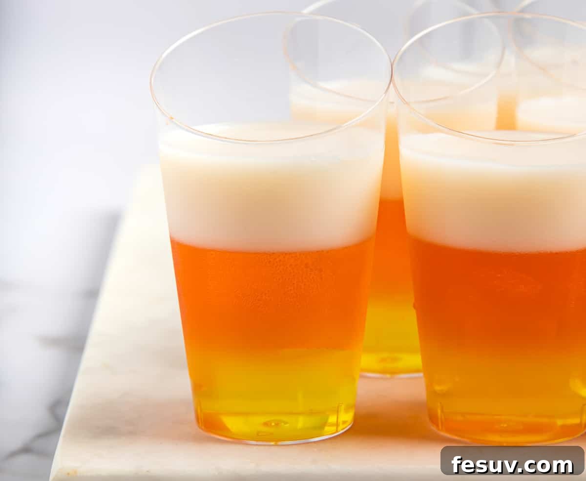 Vibrant Vodka Candy Corn Shooters 7 Jello shots with yellow, orange, and white layers.