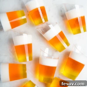 Vibrant Vodka Candy Corn Shooters 9 10 candy-corn jello shots scattered on a white table.