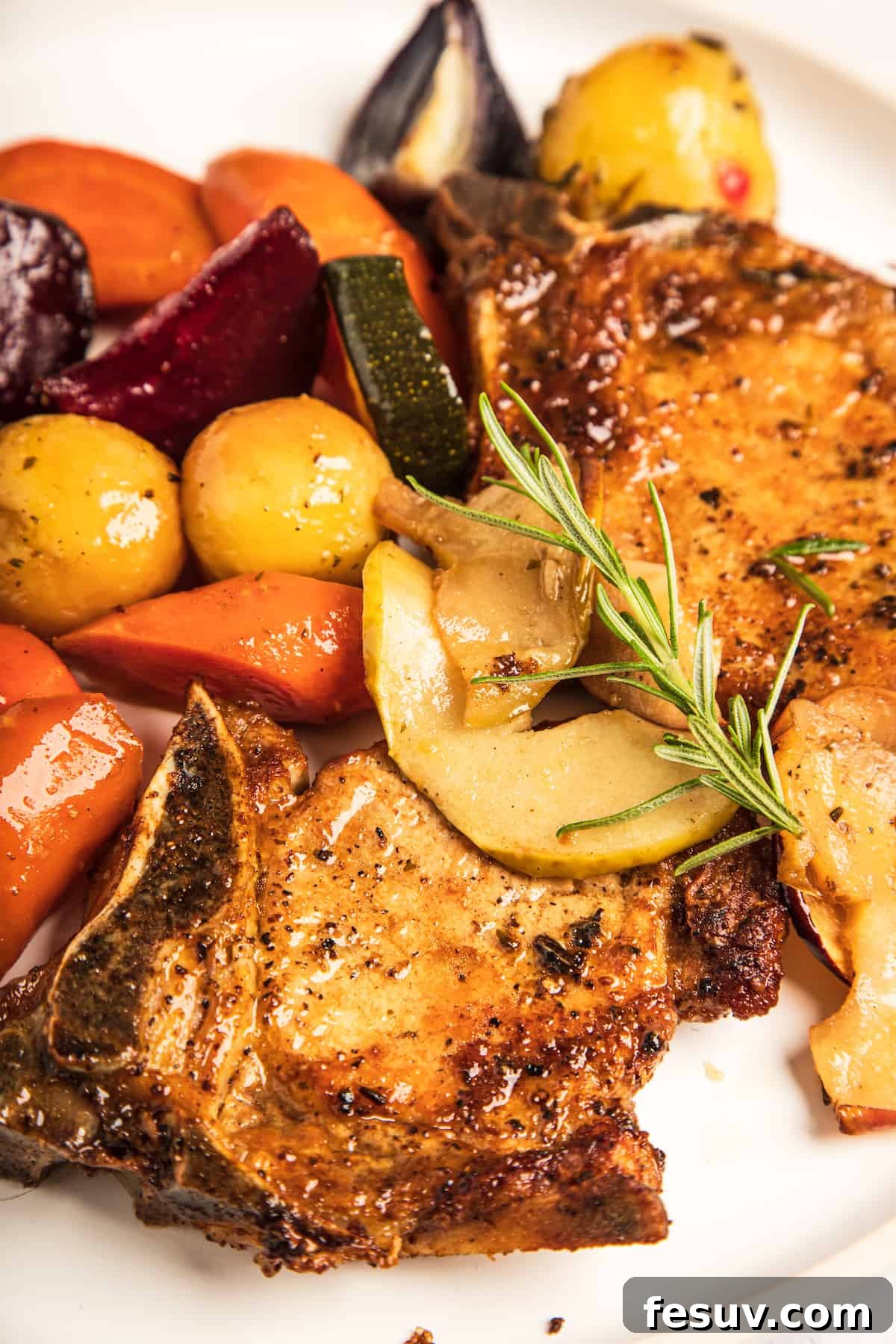 A close-up shot focusing on a perfectly seared pork chop surrounded by a vibrant mix of roasted apples and various autumn vegetables, all glistening with pan juices.