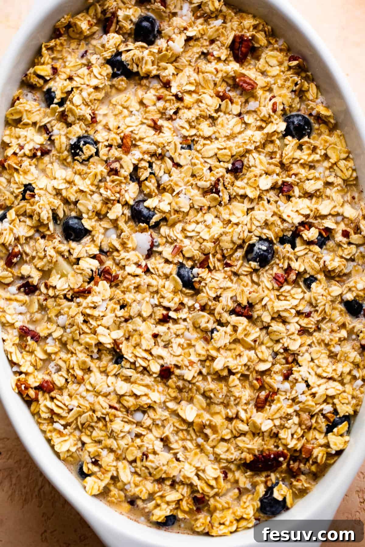 Warm Apple Blueberry Oatmeal Bake 5 oval baking dish with uncooked oatmeal with berries and apples