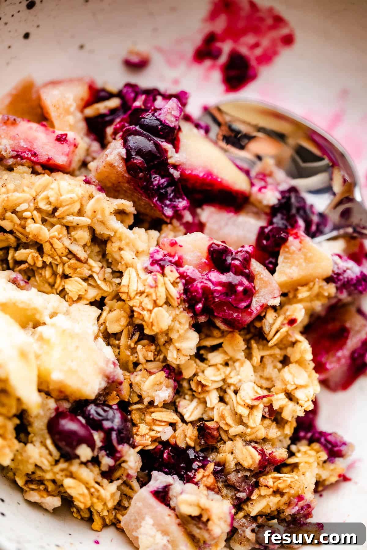 Warm Apple Blueberry Oatmeal Bake 6 a scoop of apples and berries baked oatmeal served on a white plate.