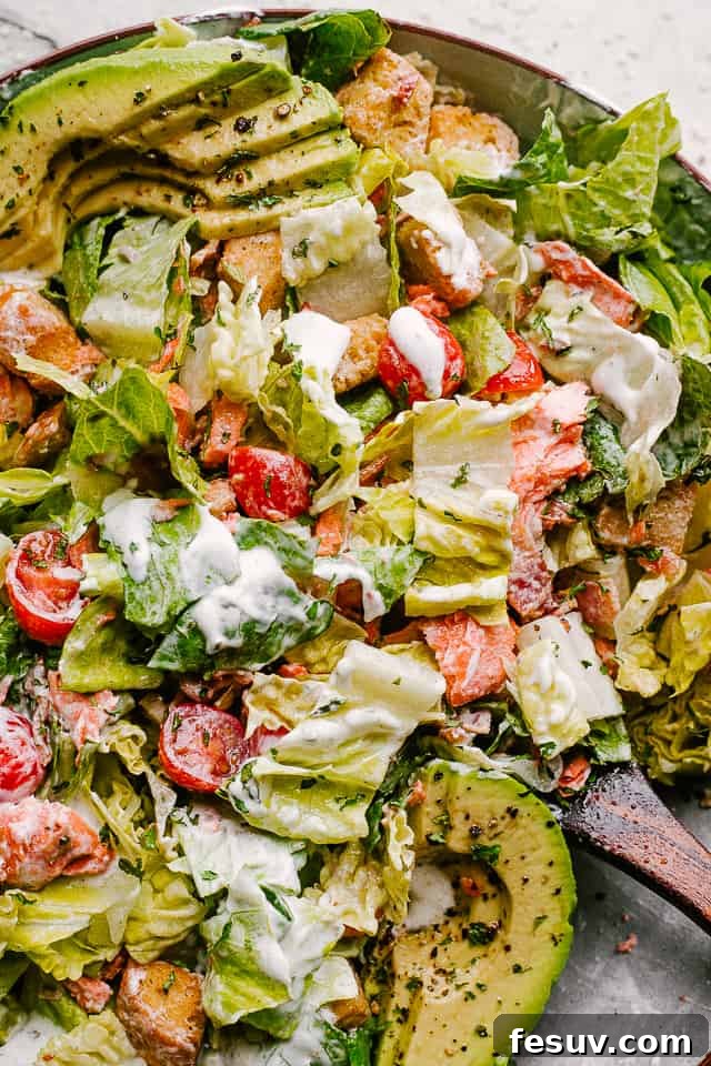 A large bowl of Salmon BLT Salad, thoroughly tossed with the creamy ranch dressing, ready for serving.