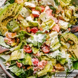 Salmon BLT salad plated with dressing mixed throughout