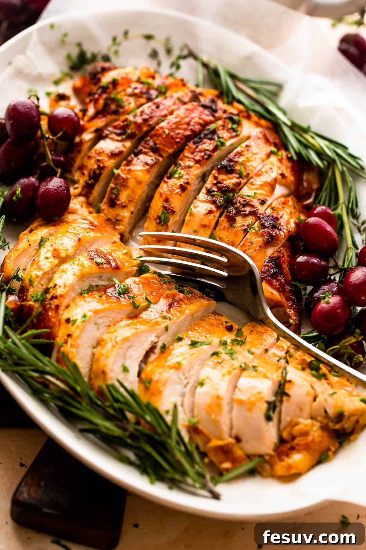Perfectly Roasted Turkey Breast 3 two turkey breasts sliced and arranged on a platter with rosemary and grape garnish