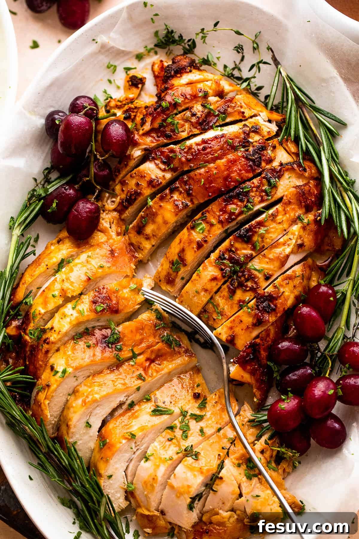 Perfectly Roasted Turkey Breast 5 two turkey breasts sliced and arranged on a platter with rosemary and grape garnish