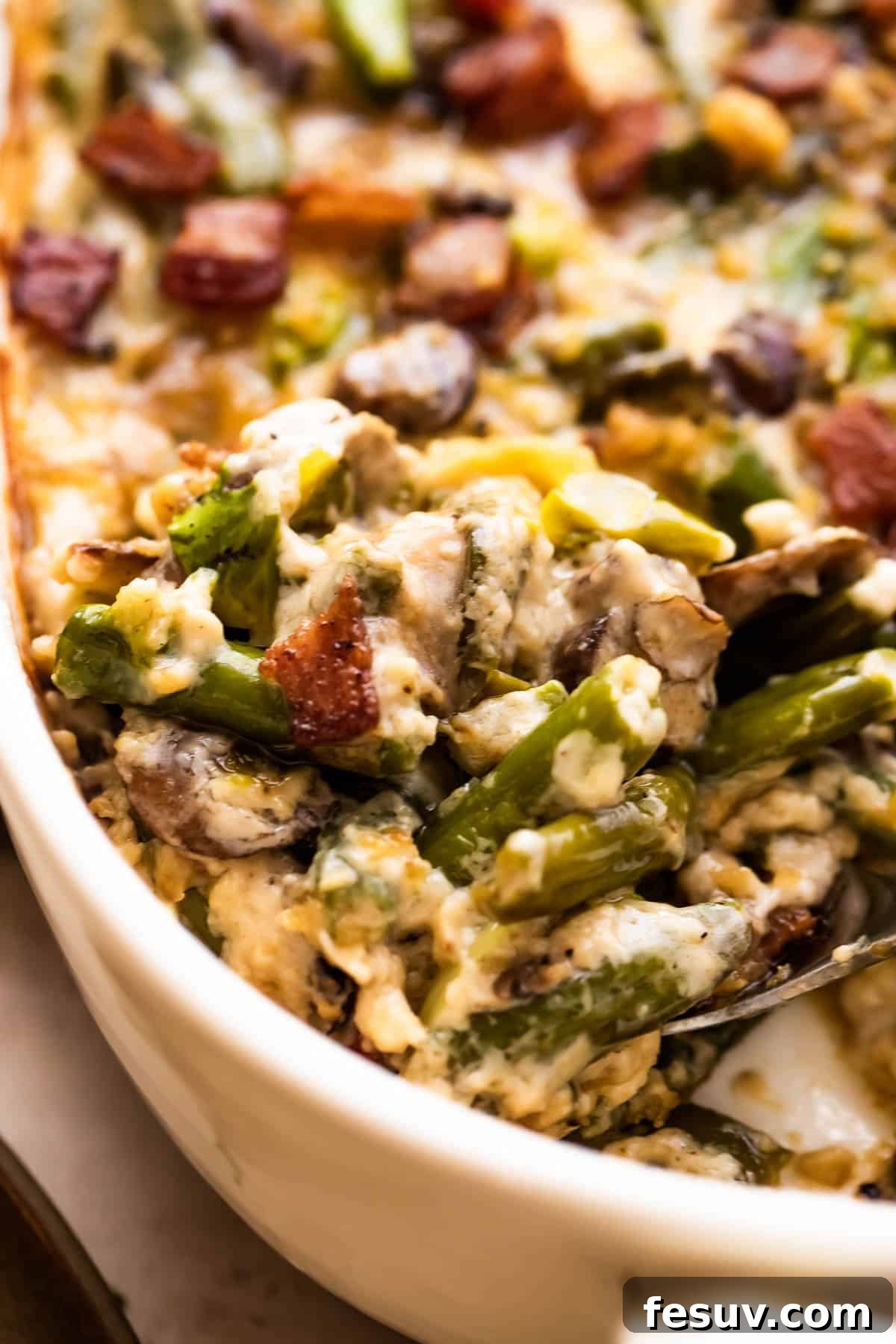 Serving Homemade Green Bean Casserole A large serving spoon scraping out a generous portion of the creamy, rich Green Bean Casserole from a white dish, highlighting its luscious texture.