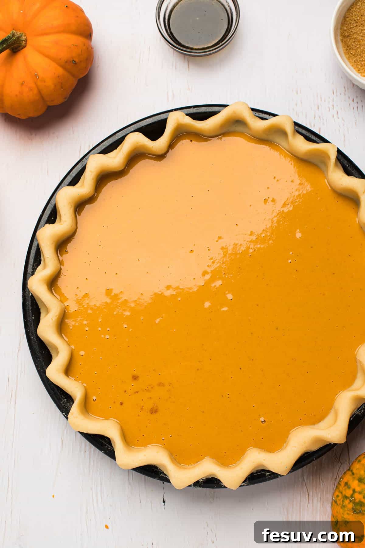 A pristine pie shell, perfectly crimped, filled with the smooth, orange pumpkin pie mixture, poised for baking.