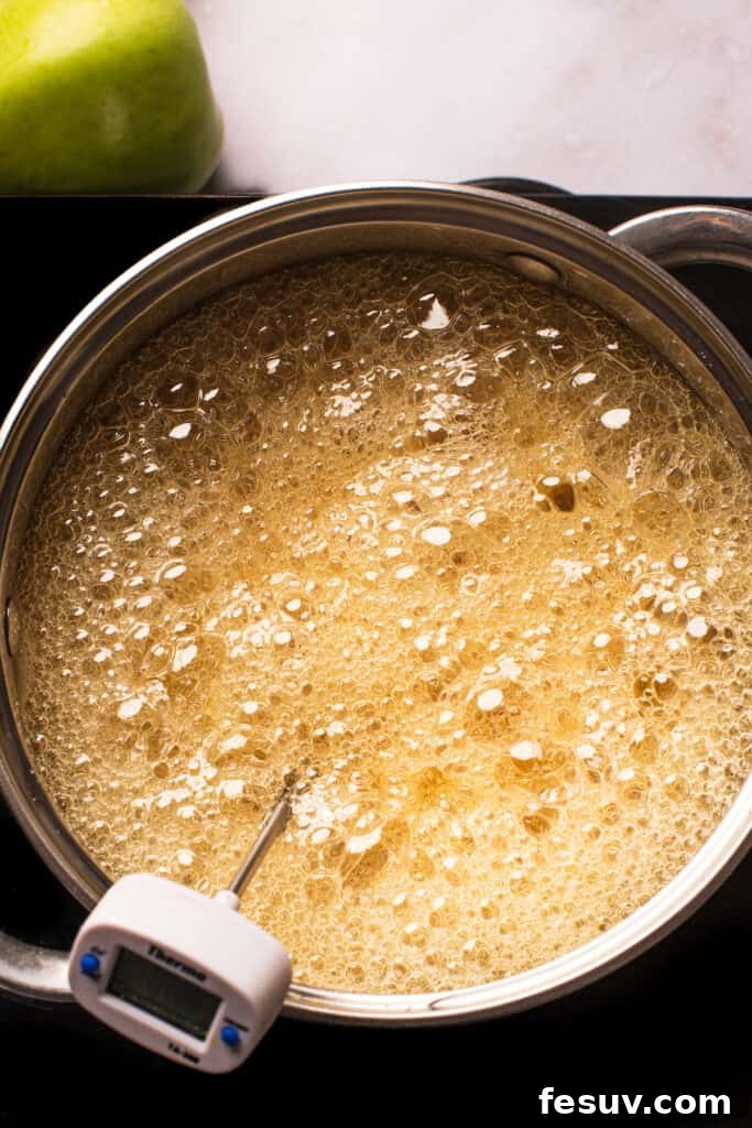 A saucepan of vigorously boiling undyed sugar candy mixture, demonstrating the active bubbling phase.