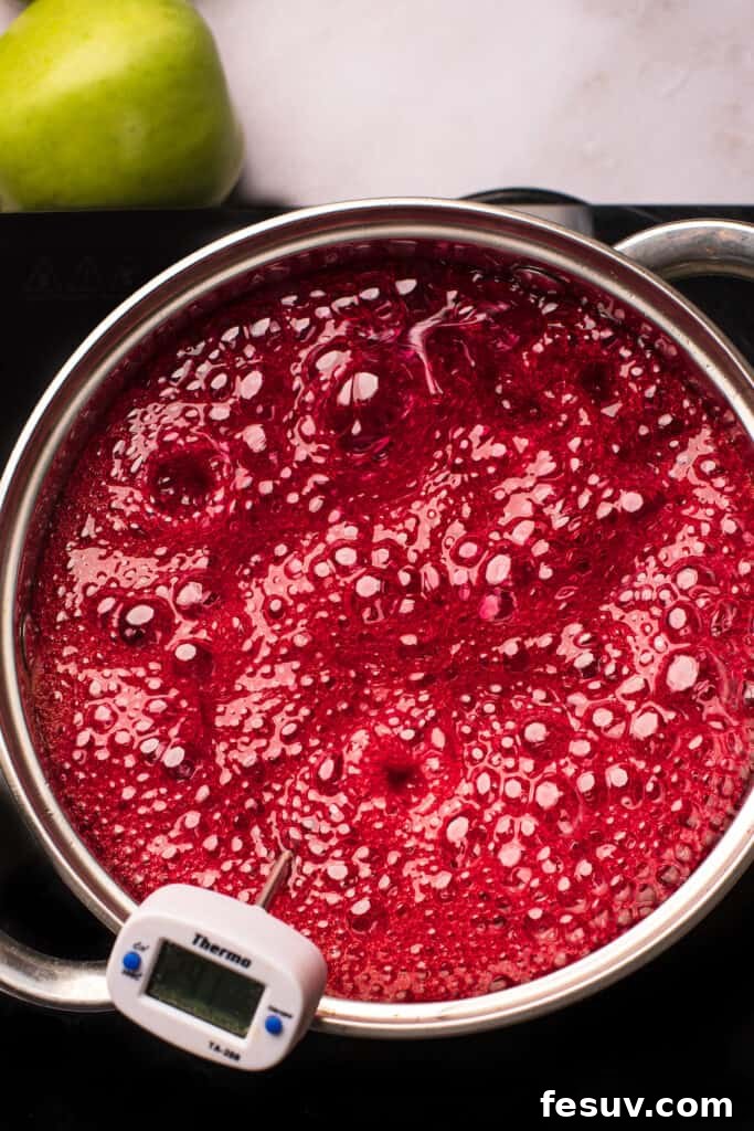 A saucepan of boiling sugar candy mixture that has been dyed a vibrant red, ready for the apple dipping process.