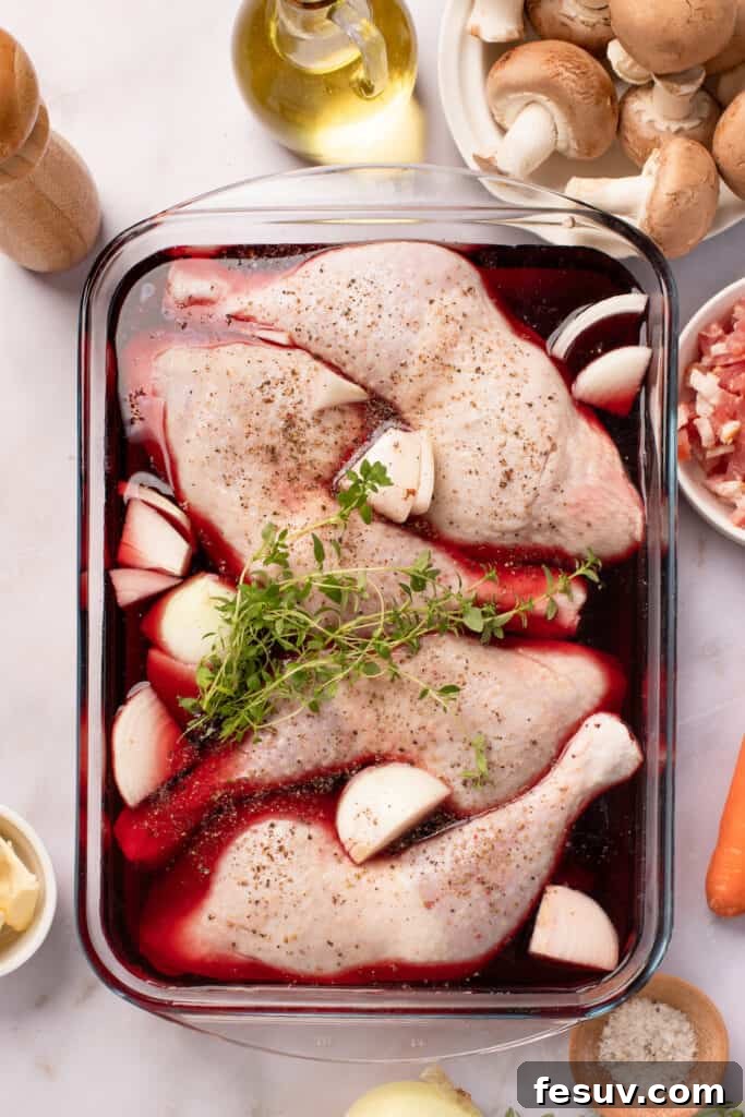 Instant Pot Coq au Vin: Classic French Flavor, Modern Speed 4 A glass baking dish with chicken leg quarters, quartered onions, and fresh thyme, all marinating in red wine. The other coq au vin ingredients are arranged around the work surface.